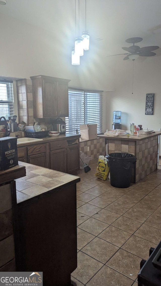 kitchen with tile patterned flooring, ceiling fan, tile countertops, and a high ceiling