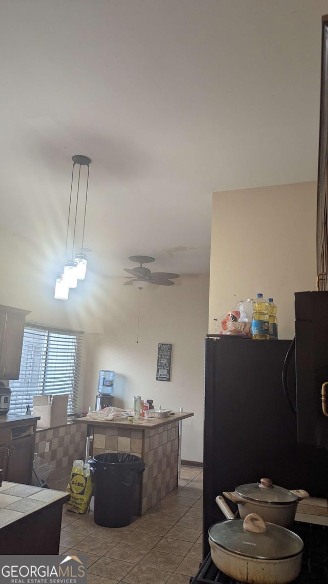 kitchen featuring tile counters, ceiling fan, freestanding refrigerator, tile patterned floors, and pendant lighting