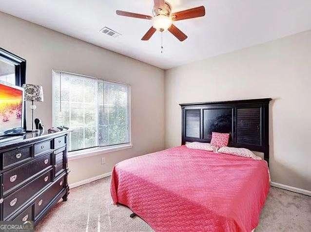 bedroom featuring baseboards, visible vents, a ceiling fan, and light colored carpet