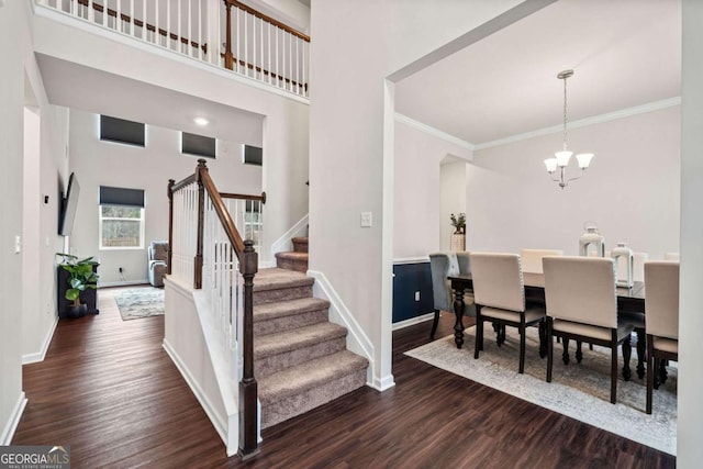 dining space with a chandelier, dark wood finished floors, stairs, and baseboards