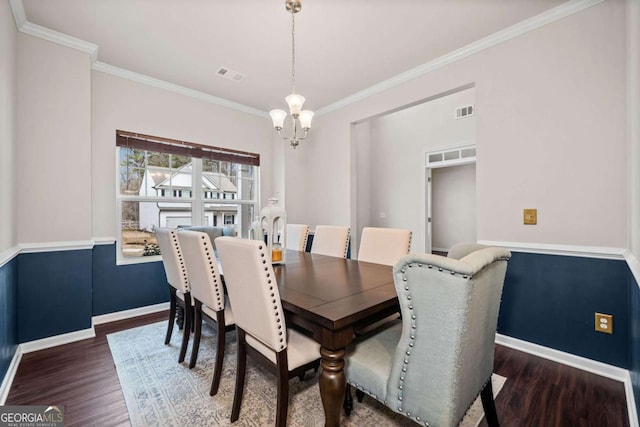 dining space featuring baseboards, visible vents, wood finished floors, and ornamental molding