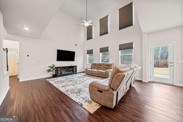 living area with dark wood-type flooring, high vaulted ceiling, and baseboards