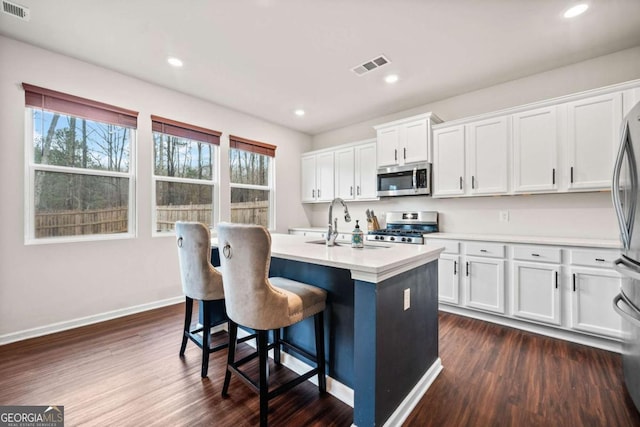 kitchen with appliances with stainless steel finishes, light countertops, white cabinetry, and dark wood-type flooring