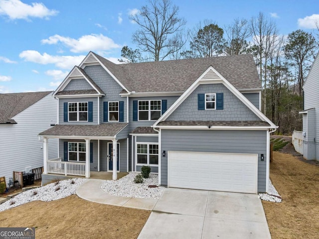 view of front of house featuring roof with shingles, covered porch, a front yard, a garage, and driveway