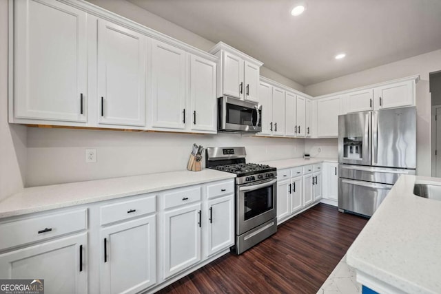 kitchen featuring dark wood-type flooring, stainless steel appliances, white cabinetry, a sink, and recessed lighting