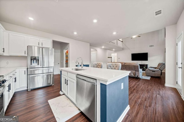 kitchen featuring appliances with stainless steel finishes, white cabinets, a sink, and dark wood-style floors