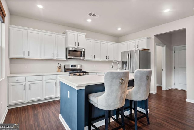 kitchen featuring stainless steel appliances, white cabinets, and visible vents