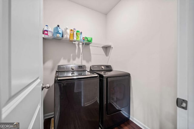 clothes washing area featuring dark wood-type flooring, laundry area, baseboards, and separate washer and dryer