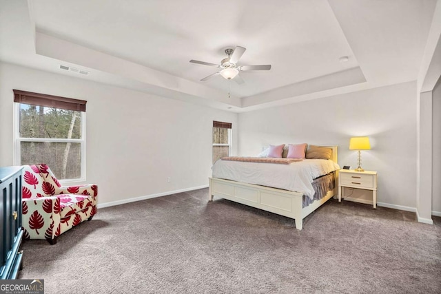 bedroom with baseboards, visible vents, ceiling fan, a tray ceiling, and carpet floors