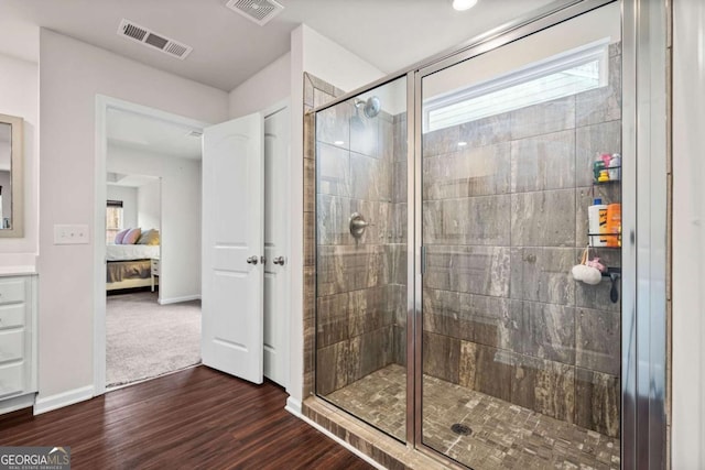 ensuite bathroom with visible vents, connected bathroom, a shower stall, and wood finished floors