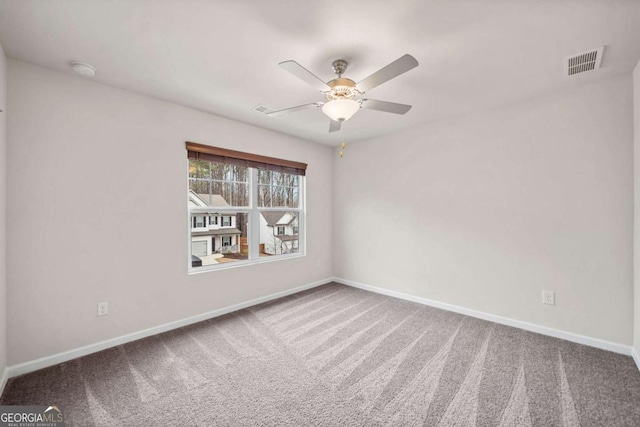 carpeted empty room featuring a ceiling fan, visible vents, and baseboards