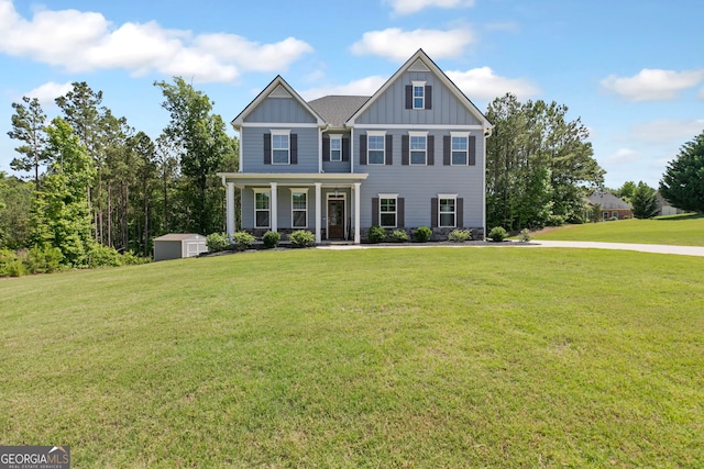 view of front of home with covered porch, a storage shed, board and batten siding, an outdoor structure, and a front lawn