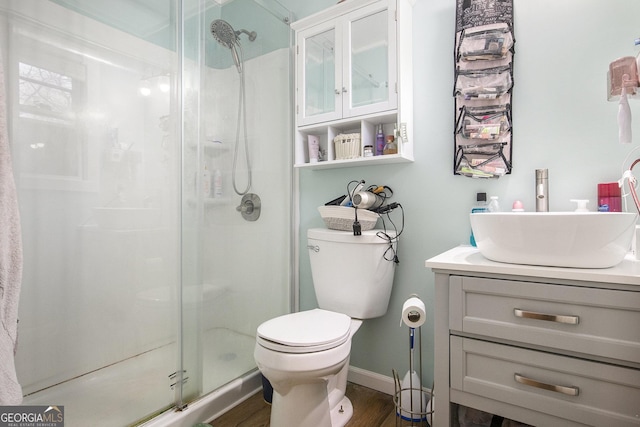 bathroom featuring vanity, toilet, wood finished floors, and a shower stall