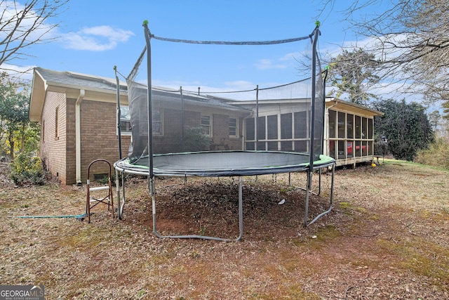 view of yard with a trampoline and a sunroom