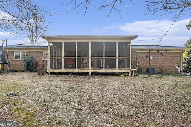 back of property featuring a trampoline, brick siding, and a sunroom