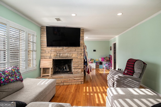 living area with visible vents, ornamental molding, recessed lighting, a fireplace, and wood finished floors