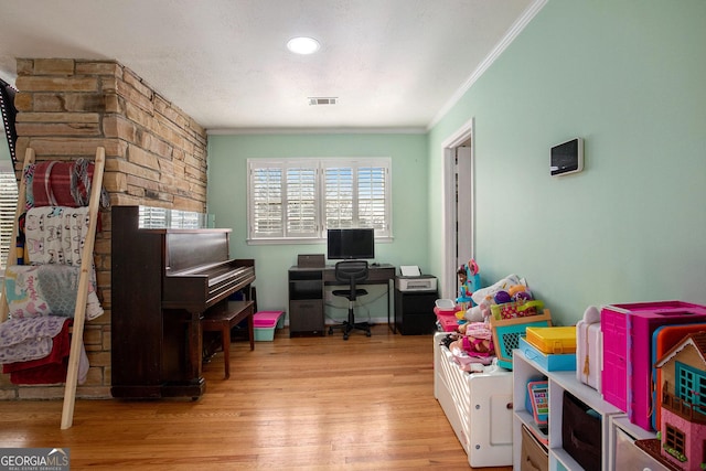 rec room with wood finished floors, visible vents, and ornamental molding