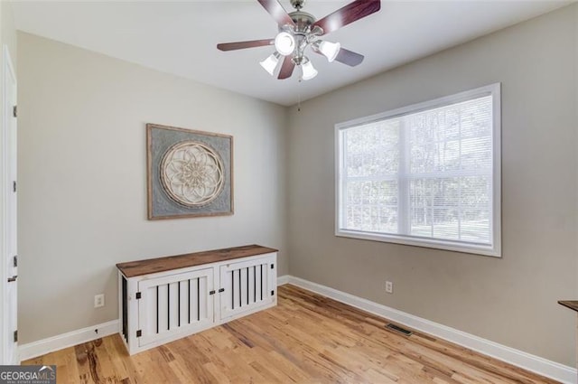 empty room with a ceiling fan, light wood-style flooring, baseboards, and visible vents