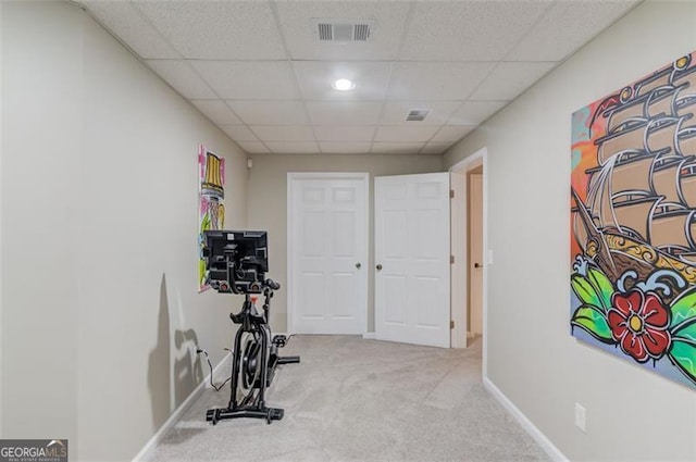 exercise room with visible vents, baseboards, a paneled ceiling, and carpet