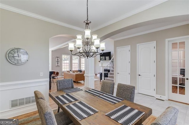 dining room with arched walkways, visible vents, stairs, and ornamental molding