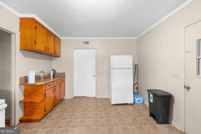 kitchen featuring visible vents, light countertops, ornamental molding, freestanding refrigerator, and brown cabinetry