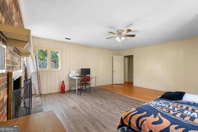 bedroom featuring a stone fireplace, wood finished floors, a ceiling fan, visible vents, and baseboards