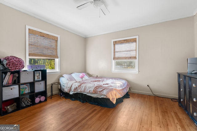 bedroom with light wood-type flooring, baseboards, a ceiling fan, and ornamental molding