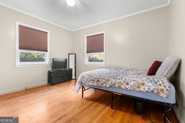 bedroom with baseboards, ornamental molding, ceiling fan, and wood finished floors