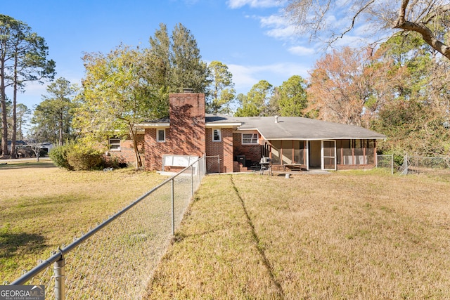 rear view of property with a sunroom, brick siding, a lawn, and a fenced backyard