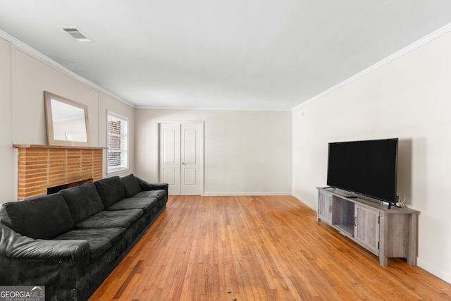 living area with light wood-style floors, visible vents, ornamental molding, and baseboards