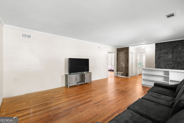 living room featuring crown molding, visible vents, and light wood-style floors