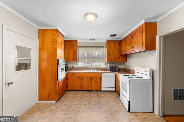 kitchen with white appliances, brown cabinetry, a sink, and visible vents