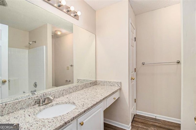 bathroom featuring a textured ceiling, baseboards, wood finished floors, and vanity