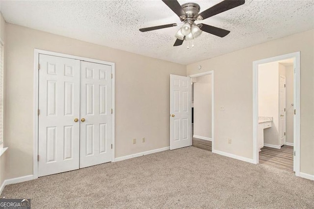 unfurnished bedroom featuring a closet, carpet flooring, a textured ceiling, and baseboards