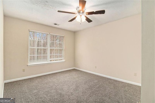 carpeted spare room featuring visible vents, ceiling fan, a textured ceiling, and baseboards