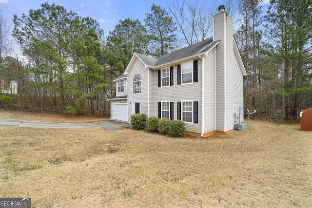 view of side of home with a garage, driveway, and a chimney