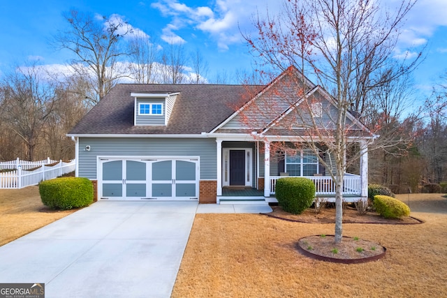 craftsman-style home with a porch, a garage, a shingled roof, brick siding, and fence