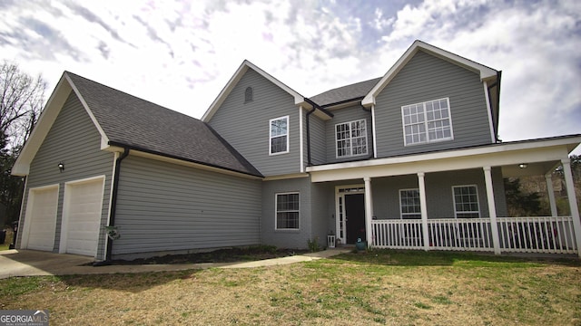 traditional-style house with roof with shingles, covered porch, an attached garage, a front yard, and driveway