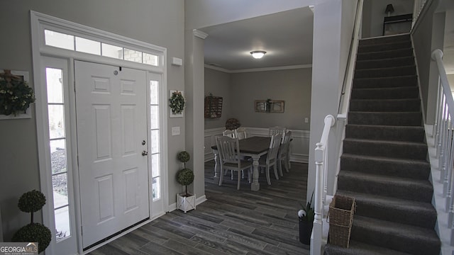 foyer featuring a wainscoted wall, stairway, ornamental molding, dark wood-type flooring, and a decorative wall