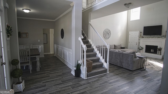 living room featuring stairs, dark wood-type flooring, a wainscoted wall, and crown molding