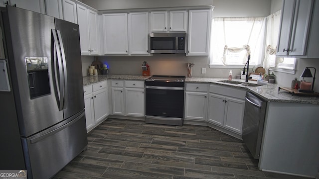 kitchen featuring appliances with stainless steel finishes, wood finish floors, a sink, and white cabinets