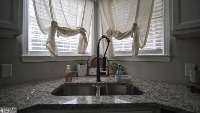 interior details featuring light stone counters and a sink