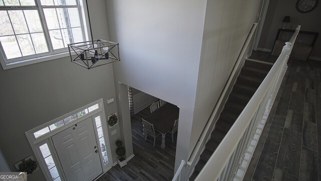 entrance foyer featuring dark wood-style floors, stairway, baseboards, and an inviting chandelier