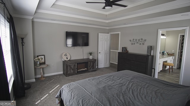 carpeted bedroom with ornamental molding, a tray ceiling, and baseboards