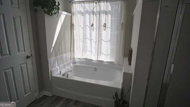 bathroom featuring wood finished floors, plenty of natural light, and a garden tub