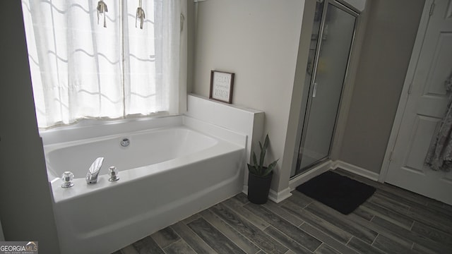 full bathroom with a stall shower, wood tiled floor, baseboards, and a bath