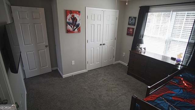 bedroom featuring a closet, dark carpet, and baseboards