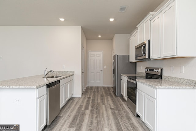 kitchen featuring visible vents, white cabinets, a peninsula, stainless steel appliances, and a sink