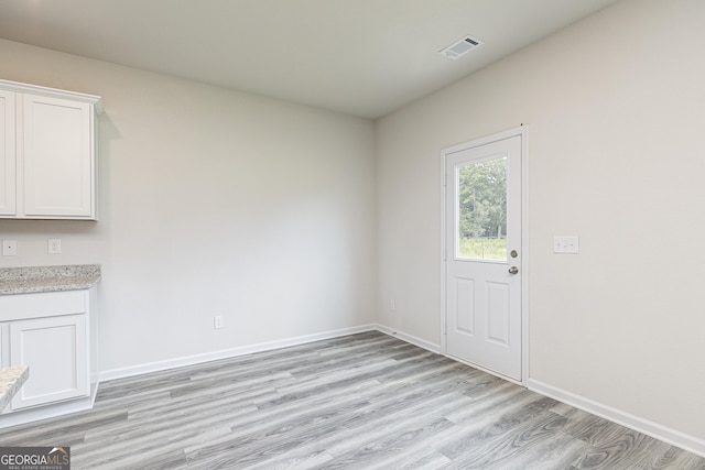 unfurnished dining area with light wood-type flooring, visible vents, and baseboards