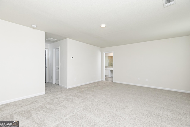 spare room with visible vents, light carpet, and baseboards